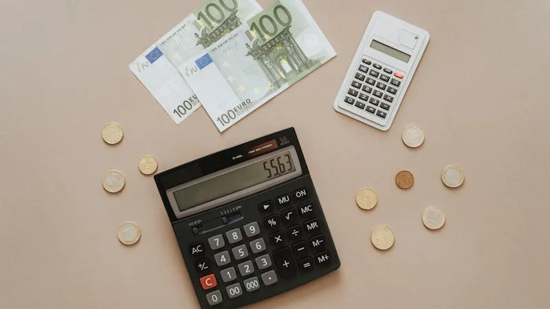 calculator and euro coins next to small house model on desk